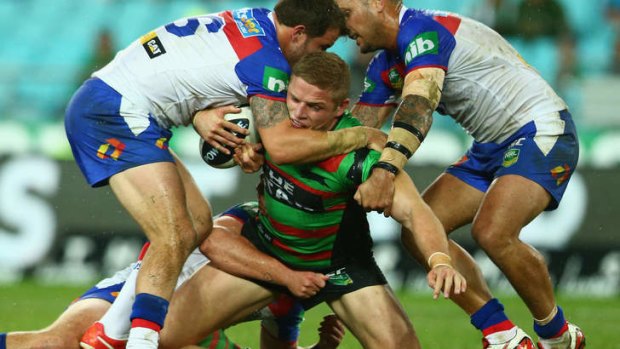 Crunched: Souths forward George Burgess is wrapped up by the Newcastle defence at ANZ Stadium.