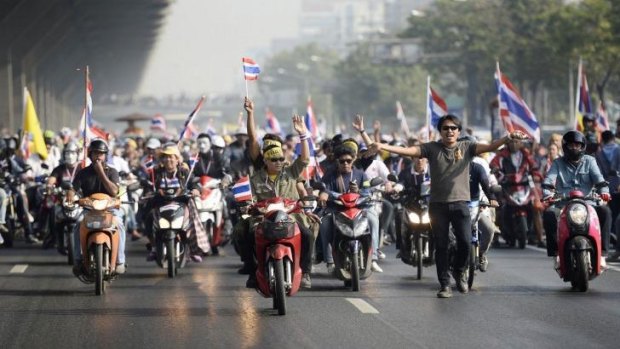 Anti-government protesters with Thai national flags ride their motorbikes as they rally on a main road in Bangkok.