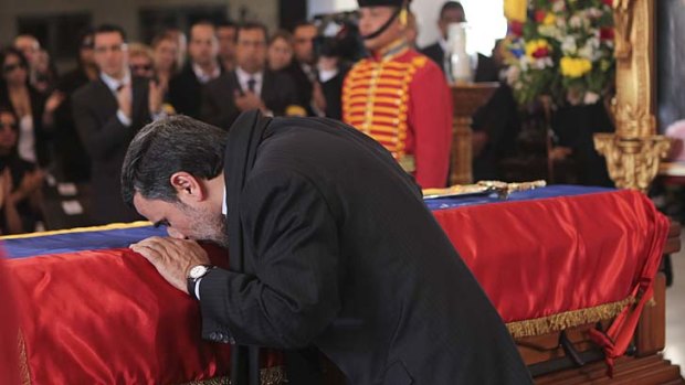 Paying tribute: Iranian President Mahmoud Ahmadinejad kisses the casket carrying Hugo Chavez.