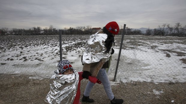 A refugee woman and a child walk in freezing weather towards the border with Serbia from a transit centre for refugees in Macedonia.