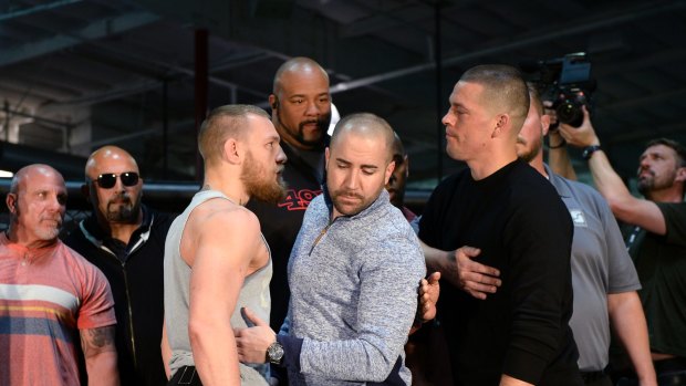 Hold me back: UFC featherweight champion Conor McGregor (left) and lightweight contender Nate Diaz (right) are held apart by Dave Sholler (centre), UFC vice-president of public relations, during their news conference in Torrance, California.  