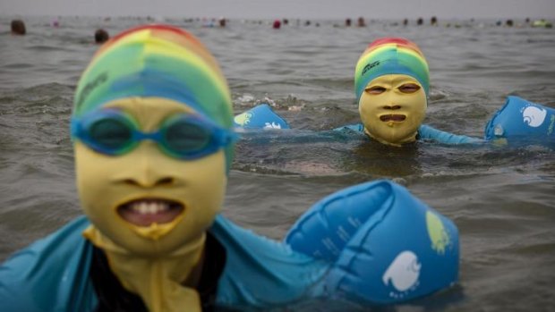 No risk of sunburn ... A Chinese woman and her daughter wear facekinis while swimming in the Yellow Sea in Qingdao, China.