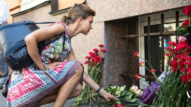 A woman lays flowers in front of the Spanish embassy in Moscow, Russia for the victims of a terrorist attack in Spain. 