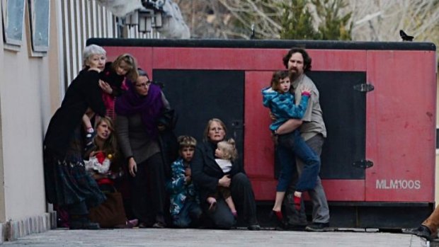 Foreigners hold children as they take refuge behind a generator outside a guesthouse.