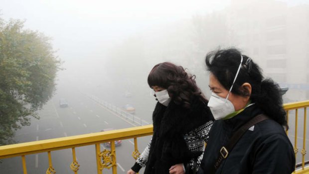 Pedestrians wearing masks walk along a road as heavy smog engulfs the city in Harbin, China.