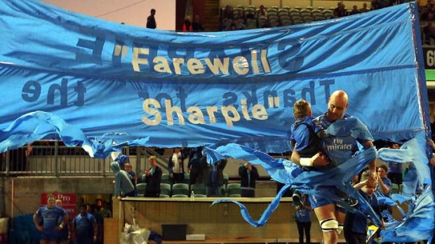 The end ... Nathan Sharpe runs through a banner with his children ahead of his last game in Perth.