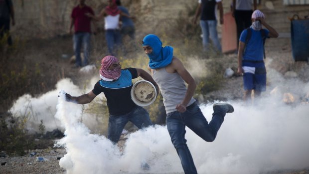 A Palestinian protester throws back a tear gas canister that was fired by Israeli troops during clashes near Ramallah, West Bank, on October Thursday.