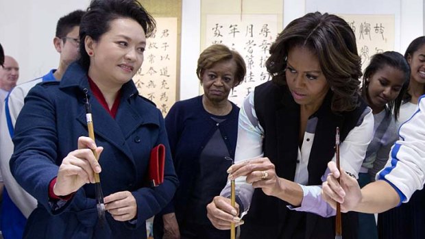 Peng Liyuan instructs Michelle Obama in calligraphy at a school in Beijing.