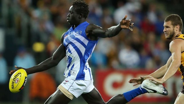 In full flight: Majak Daw gets his kick away in front of Mitch Hallahan.