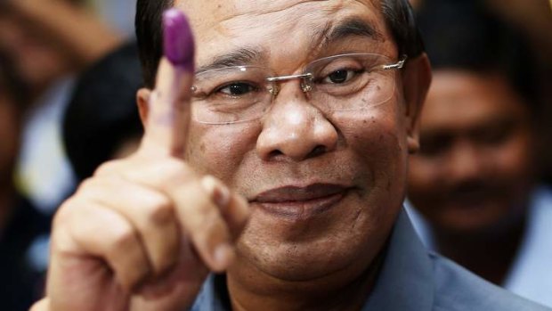 Cambodia's Prime Minister Hun Sen shows his ink-stained finger after voting.