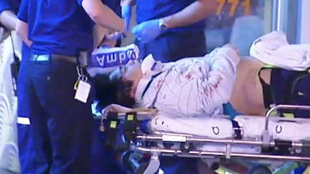 An injured man is lies on an ambulance trolley following a brawl outside a karaoke bar in Glen Waverley.