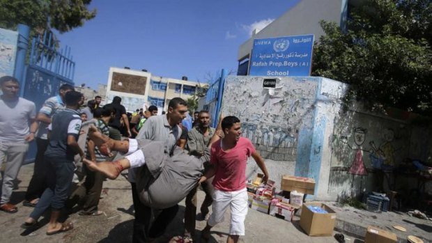 Palestinians carry a wounded man after an Israeli air strike at a UN school in Rafah on August 3.