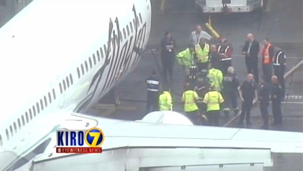 Workers help a cargo worker after he was removed from the cargo hold of an Alaska Airlines jet at Seattle-Tacoma International Airport after the LA-bound flight returned.