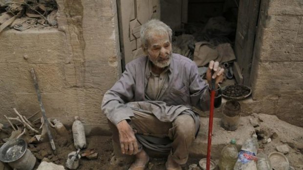 A man sits in front of his damaged house in Aleppo after surviving   an apparent  barrel bomb dropped by Syrian forces.