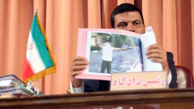 Iranian judge Abul Qasim Salavati shows a picture taken during the post-election riots in Iran as he presides over the trial of suspected opposition supporters in a courtroom in Tehran.