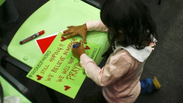 The four-year-old daughter of an MH370 crew member writes a message during a 100 days of remembrance event in Kuala Lumpur on June 15.