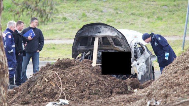 Police examine the burnt remains of a car near Cemetery Road in Keilor East.