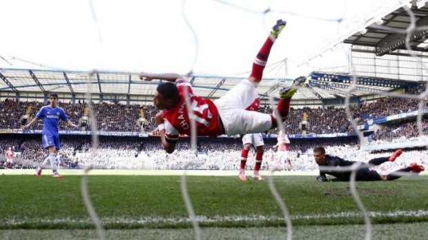 Arsenal outfielder Alex Oxlade-Chamberlain dives to save a shot at goal by Chelsea with his hand.
