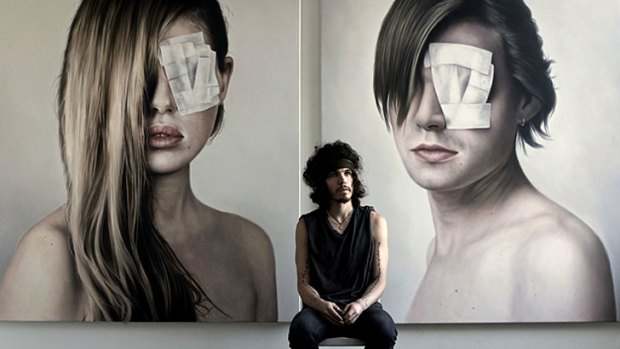 Matt Doust in front of two portraits from his 'Unravel' exhibition.