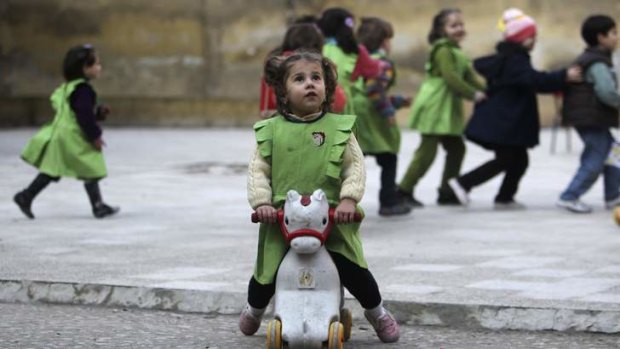 A girl looks up to the sky after hearing the sound of shelling near her school in Aleppo.