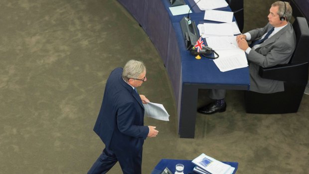 Jean-Claude Juncker, returning to his seat after speaking, walks past former UK Independence Party leader Nigel Farage, a member of the European Parliament and champion of Brexit.