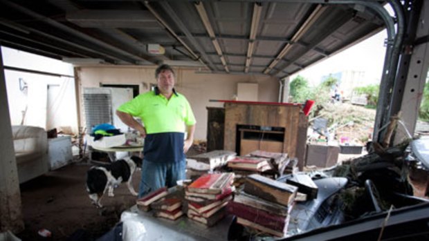 "Well, we're alive" ... Barry Bull surveys the damage to his family's home in the Withcott area. They escaped the flood by climbing into the roof cavity.