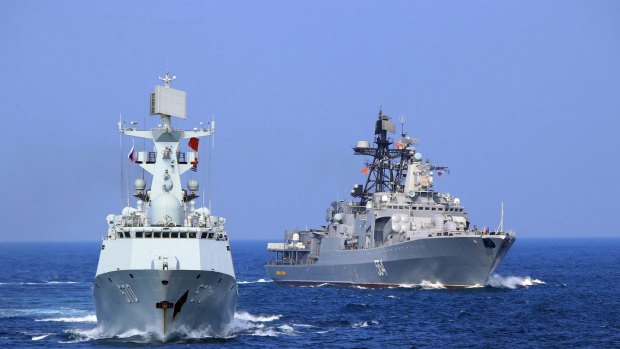 Chinese Navy frigate Huangshan, left, and Russian Navy antisubmarine ship Admiral Tributs take part in a joint naval drill in the South China Sea.