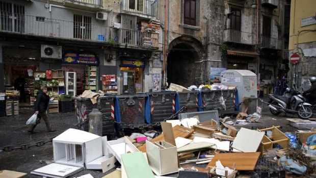 Garbage strewn around trash cans outside a store in Naples, Italy.