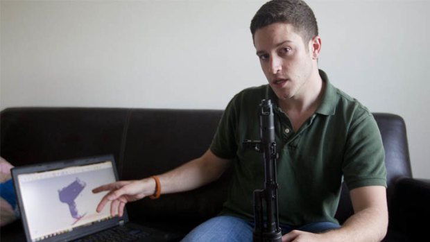 "Wiki Weapons" project leader Cody Wilson points to his laptop screen displaying an image of a prototype plastic gun on the screen, while holding in his other hand a weapon he calls "Invivdual Mandate", in Austin, Texas.