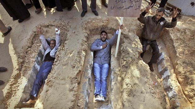 People in Zawiya, eastern Libya, lie in open graves to show their willingness to die.