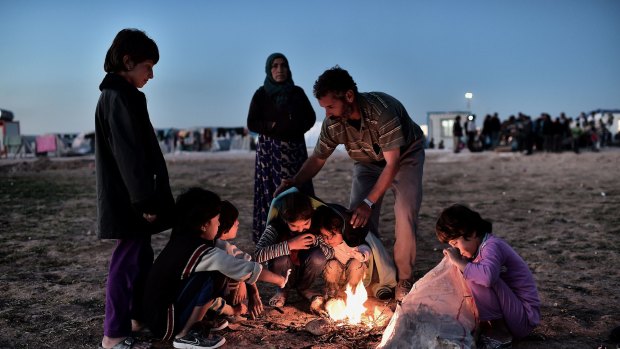 The world's growing indifference: Syrian Kurdish refugees try to get warm around a fire at a refugee camp in the town of Suruc, Turkey. 