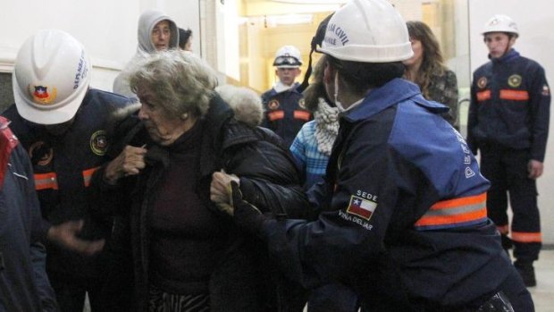 Civil Defence volunteers help an elderly woman evacuate her building after the earthquake.