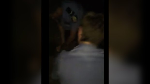 The video appears to show a police officer punching a woman who is pinned to the ground.