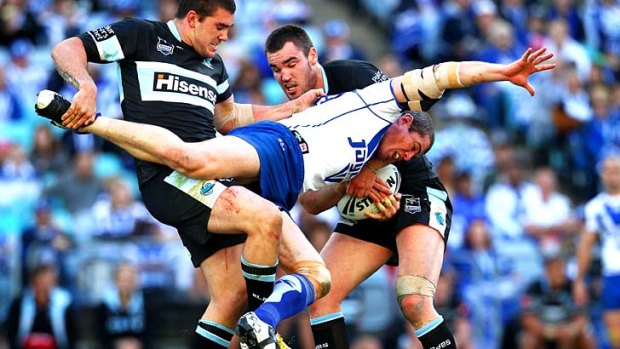 Andrew Ryan runs into some heavy defence form by Kade Snowden and Luke Douglas of the Sharks.