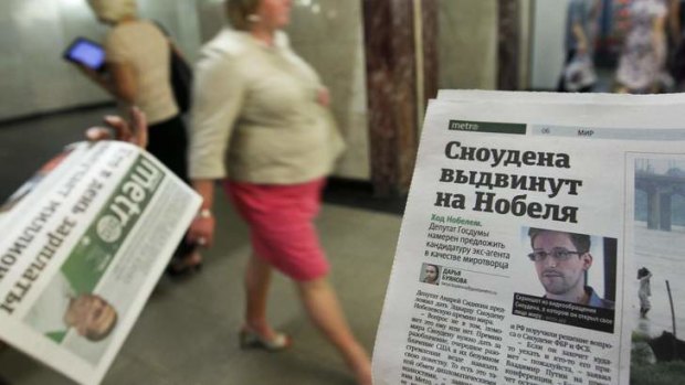 An employee distributes newspapers, with a photograph of Edward Snowden seen on a page, at an underground walkway in central Moscow.