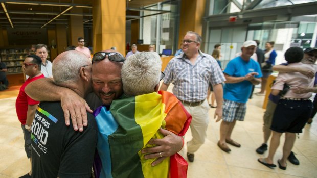 Eric Hause of Norfolk, centre, hugs Claus Ihlemann and Robert Roman in the lobby of the Slover Library Friday morning, in Norfolk, Virginia. 