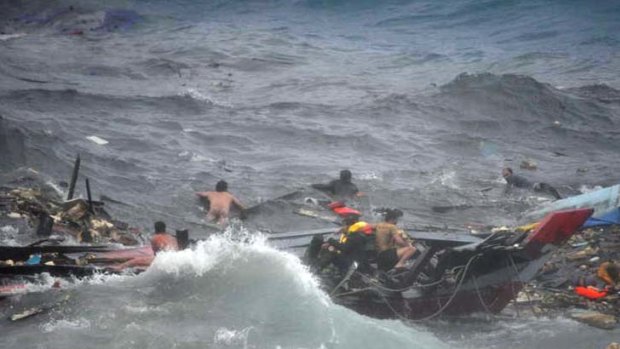 Struggling ... people cling to the wreckage of their boat after it smashed against the Christmas Island coast.