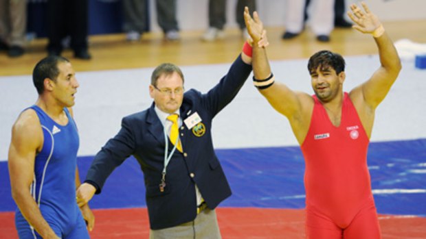 The decision ... India's Anil Kumar is awarded the gold medal, as Australia's Hassene Fkiri looks on.