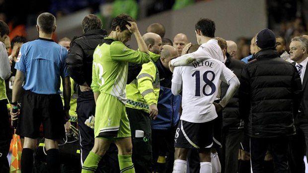 Helpless ... Players and officials console one another after Muamba is stretchered from the pitch. Reports said his heart failed to beat on its own for two hours before he reached hospital.