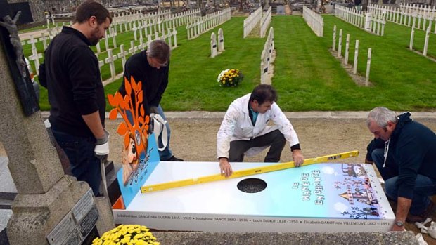 The future is here ... workers install an 'iron grave' at a cemetery in Nantes for TV show creator Serge Danot, who died in 1990.