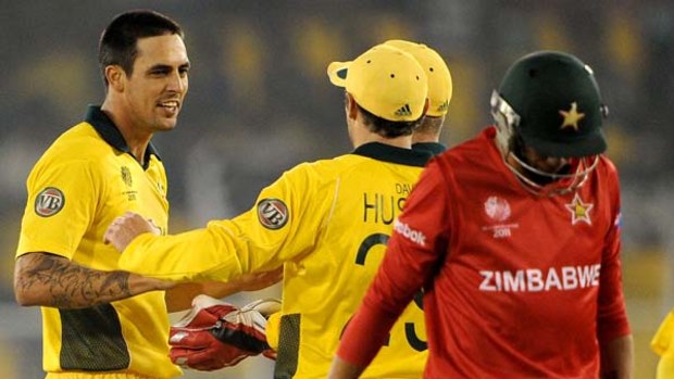Mitchell Johnson is congratulated by teammates after dismissing Zimbabwean batsman Graeme Cremer.