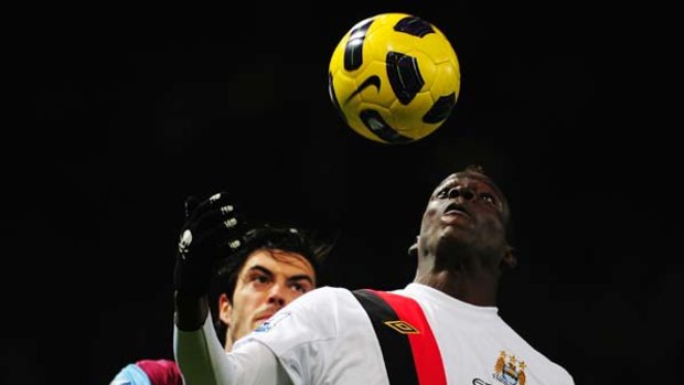 Mario Balotelli of Manchester City controls the ball ahead of James Tomkins of West Ham United.