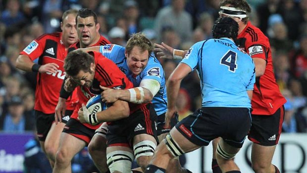 The Crusaders Richie McCaw gets tackled by Waratahs Rocky Elsom.