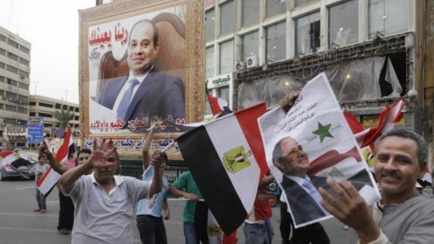 Likely victor ... Supporters of presidential candidate former army chief Abdel-Fattah el-Sissi hold his posters and wave national flags as they celebrate during the second day of presidential elections in Cairo.