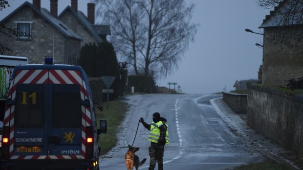 A Police officer walks on the road outside Longpont on January 9, 2015 in Longpont, France. A huge manhunt for the two suspected gunmen in Wednesday's deadly attack on Charlie Hebdo magazine has entered its third day. 