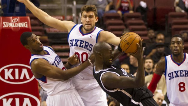 Brooklyn Nets forward Kevin Garnett battles for a rebound with Philadelphia 76ers' Spencer Hawes , center, and Thaddeus Young, left, during the second quarter of a preseason NBA basketball game on Monday.