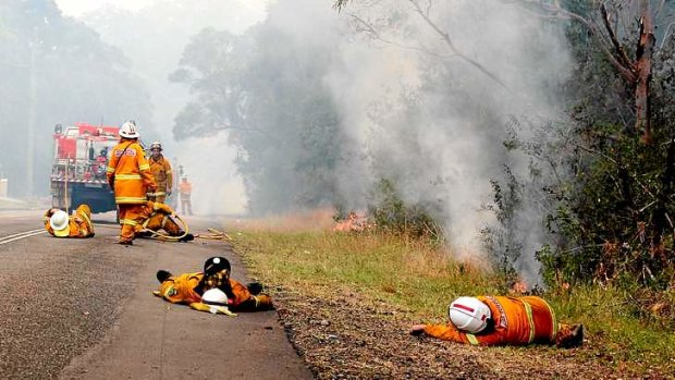 Beyond exhaustion: Firefighters grab a few moments rest in Cranagan Bay Road, at Nords Wharf on Lake Macquarie