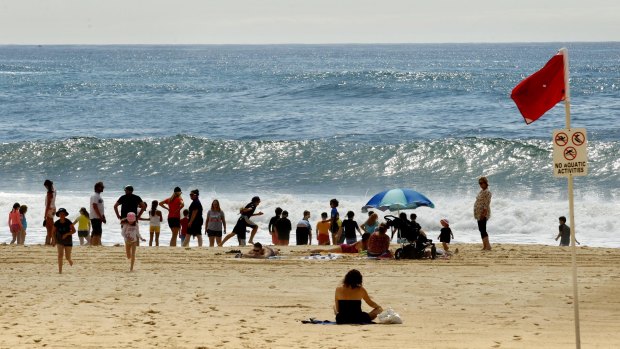 People sit on Nobbys Beach on Tuesday after it was closed.