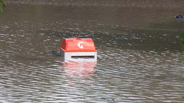 Submerged ...a Telstra phone booth under floodwater in Fairfield in southern Brisbane.