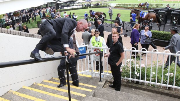 Up and over: Retiring Jockey Jimmy Cassidy jumps the fence to sign autographs. Photo: bradleyphotos.com.au